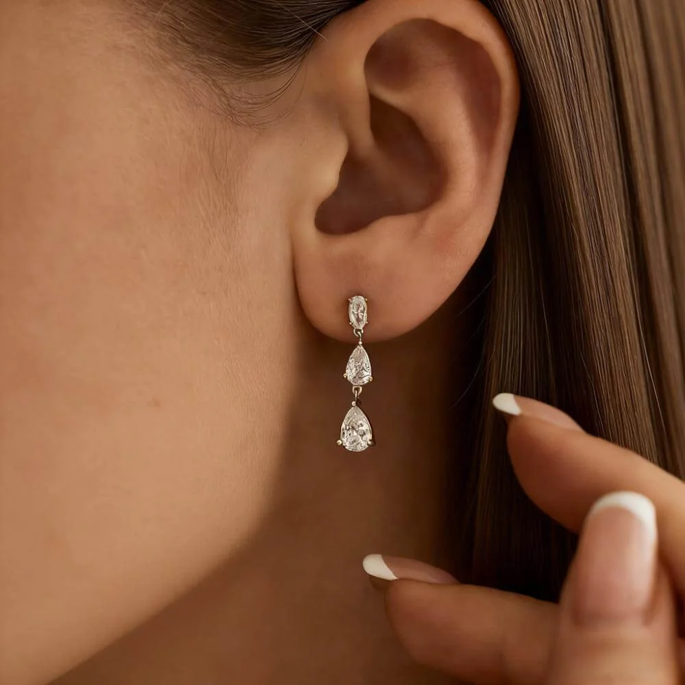 Macro close-up of a model’s ear wearing diamond earrings, showing sparkle and setting detail.