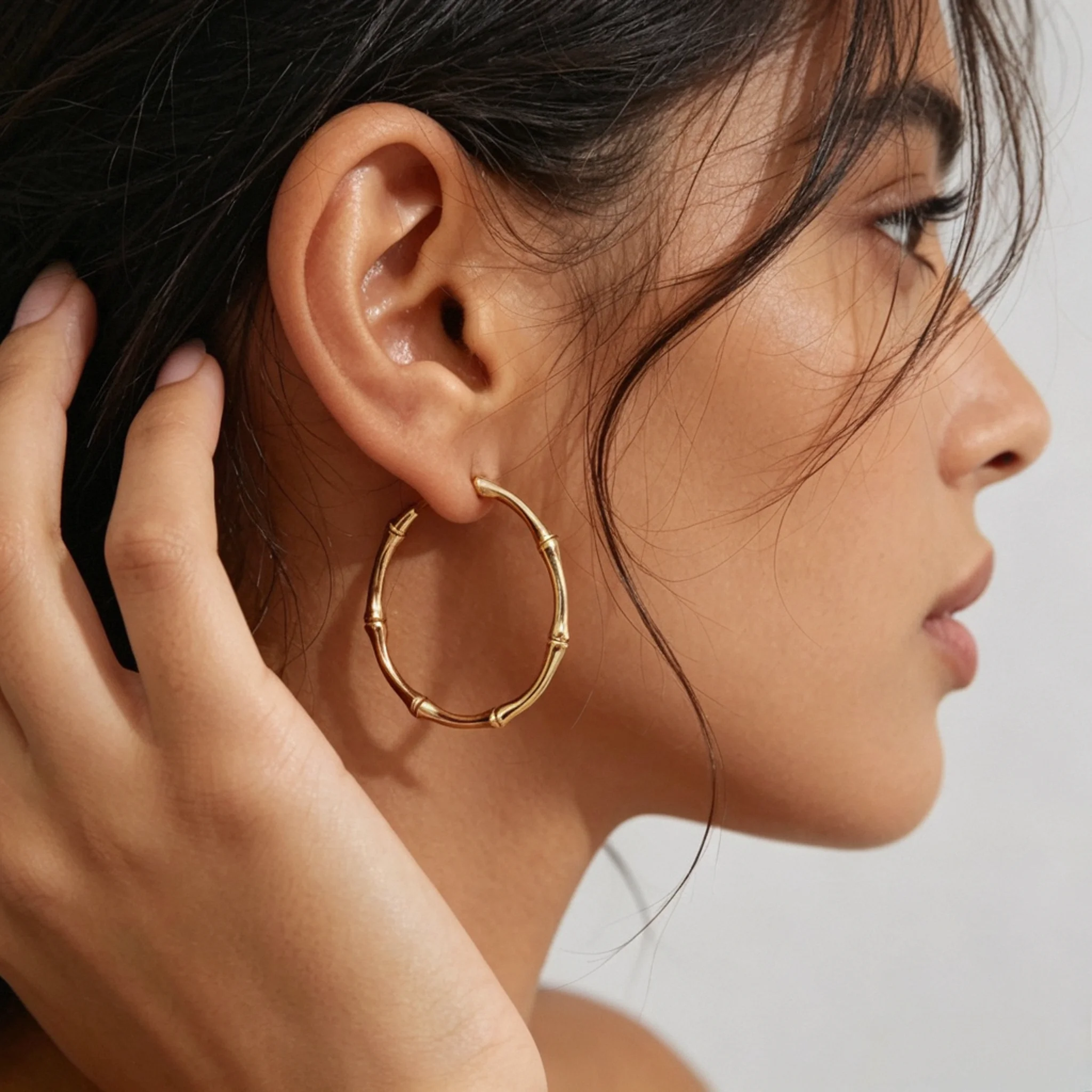 gold bamboo hoop earrings shown on AI ear model
