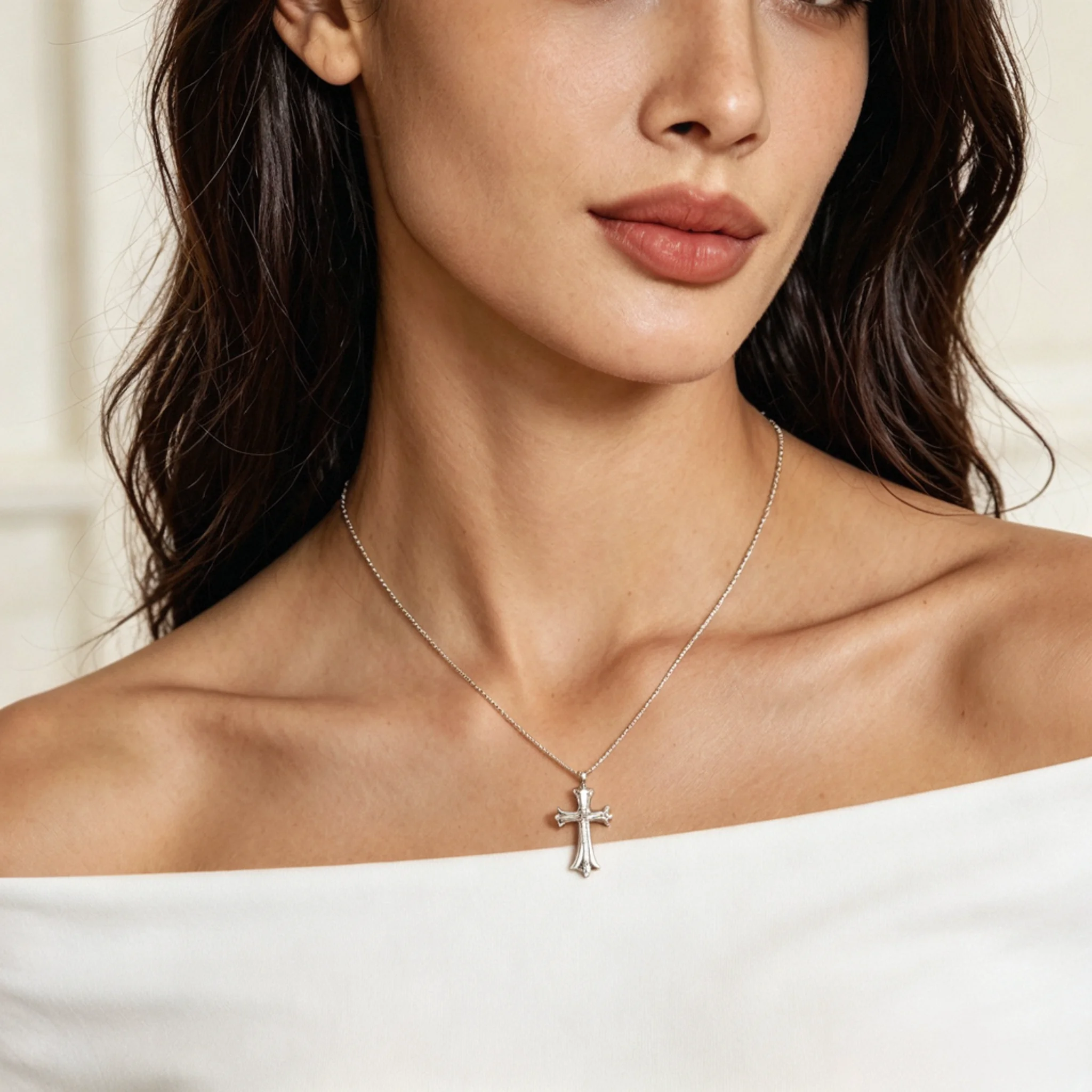 Model styled with a silver cross necklace, upright pendant, and clear symbol shape