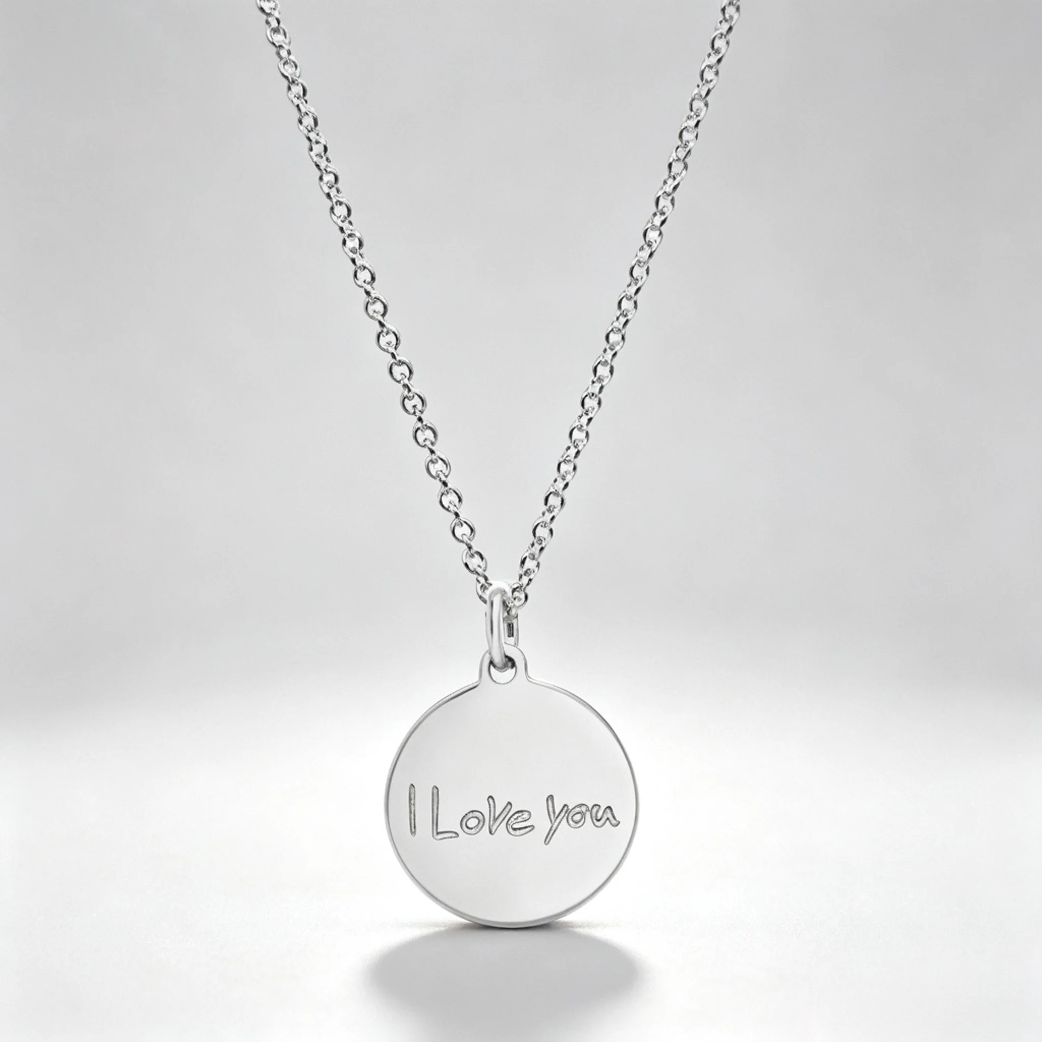 Silver engraved disc necklace with a short message, circular border, and top loop