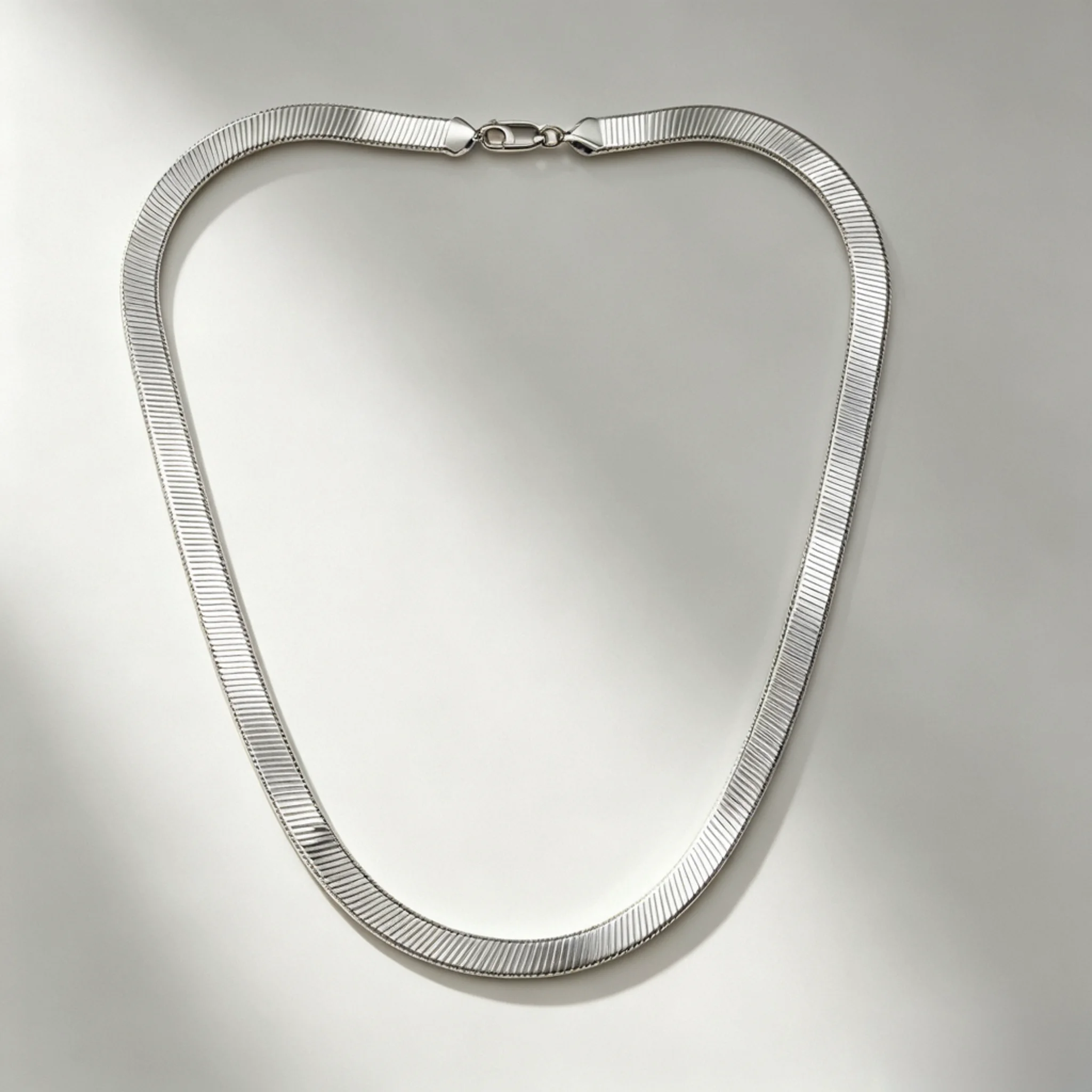 Silver herringbone necklace laid flat with close-set V links and a broad center band